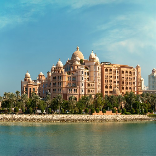 Picture of a large palace‑style building with domes, surrounded by palm trees along the waterfront